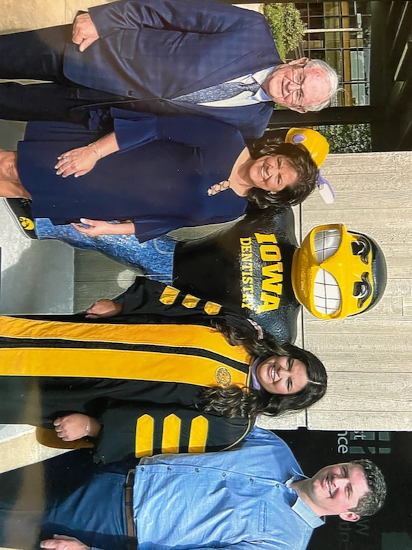 Dr. Lynn Curry with his family taking a photo with the mascot statue of Herky the Hawk with a shirt that says Iowa Dentistry.