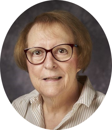 Portrait of Dr. Geraldine R. Hall, wearing glasses and a light striped shirt, against a dark studio background.