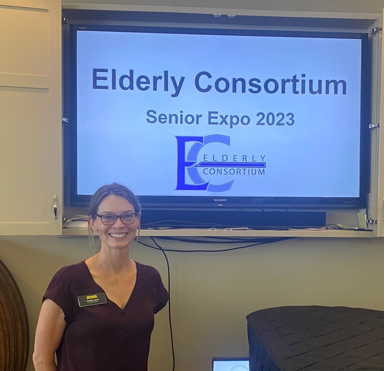 A women is standing in front of a screen that reads "Elderly Consortium."