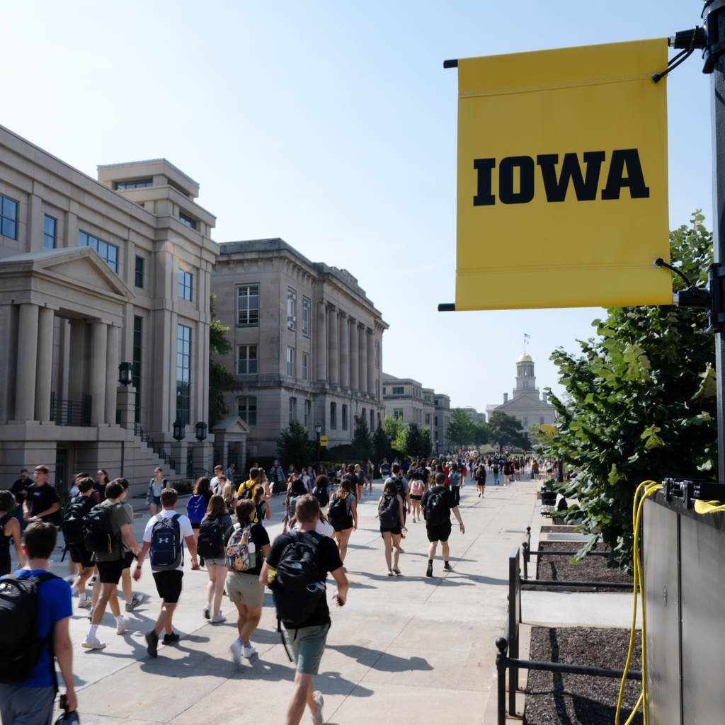 A crowd of students walks toward the Old Capitol building.