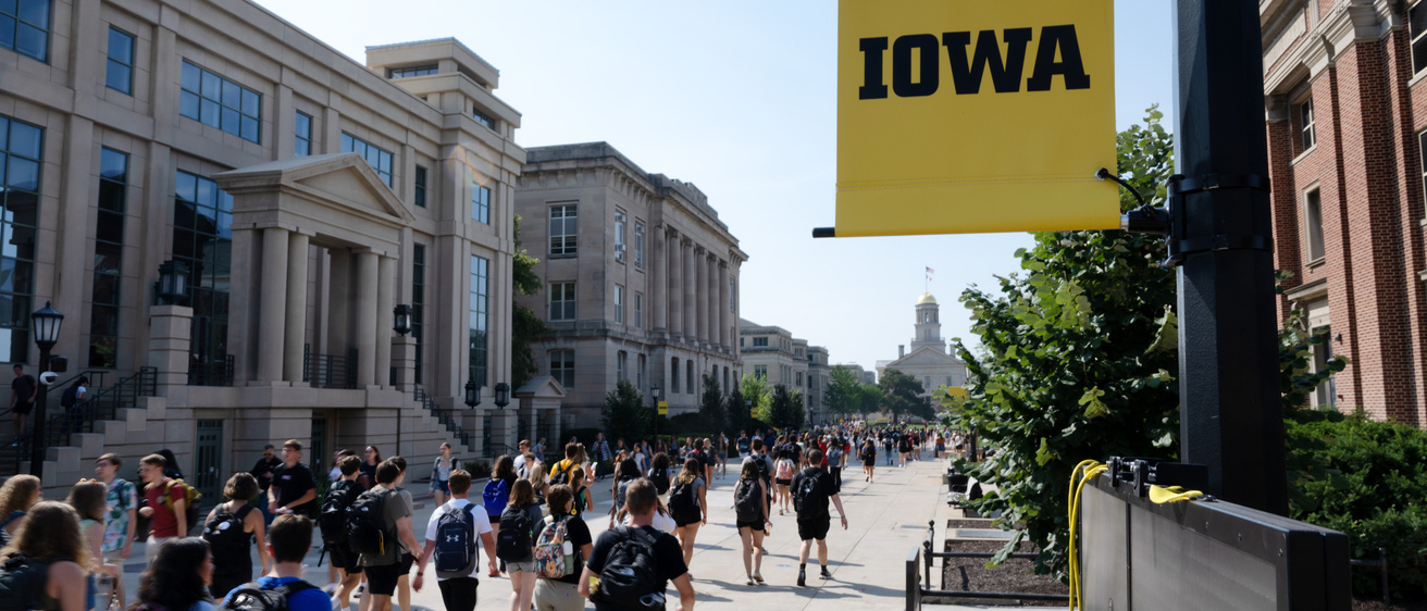 A crowd of students walks toward the Old Capitol building.