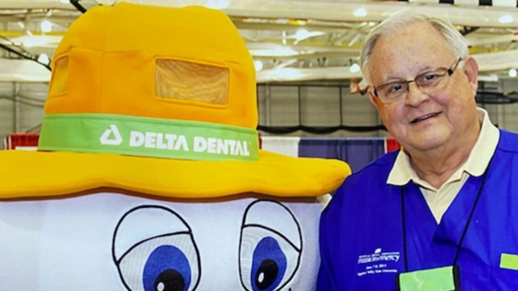 Dr. Lynn Curry smiles and poses for a photo with the Delta Dental Tooth mascot.
